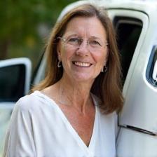 Helen smiling by her shiny white SUV